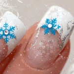 Close-up of a woman's winter-themed forum profile photo: glittery white nails with blue snowflake nail art and silver sparkle.