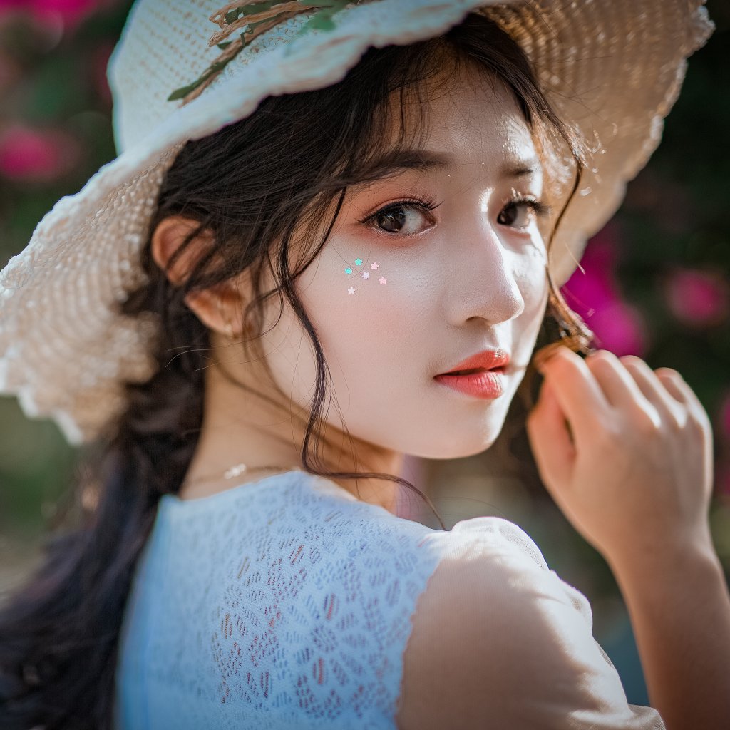 Close-up forum avatar of a brunette woman model with brown eyes and lipstick wearing a straw hat, glancing over her shoulder toward the camera.