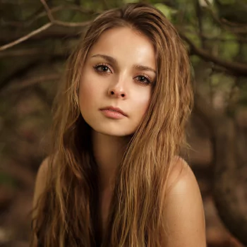 Profile avatar of a brunette model with long hair and brown eyes, neutral expression against a soft outdoor background.