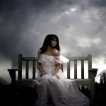 Dark gothic-themed forum avatar showing a woman in a flowing white dress sitting on a bench under a moody, cloudy sky.
