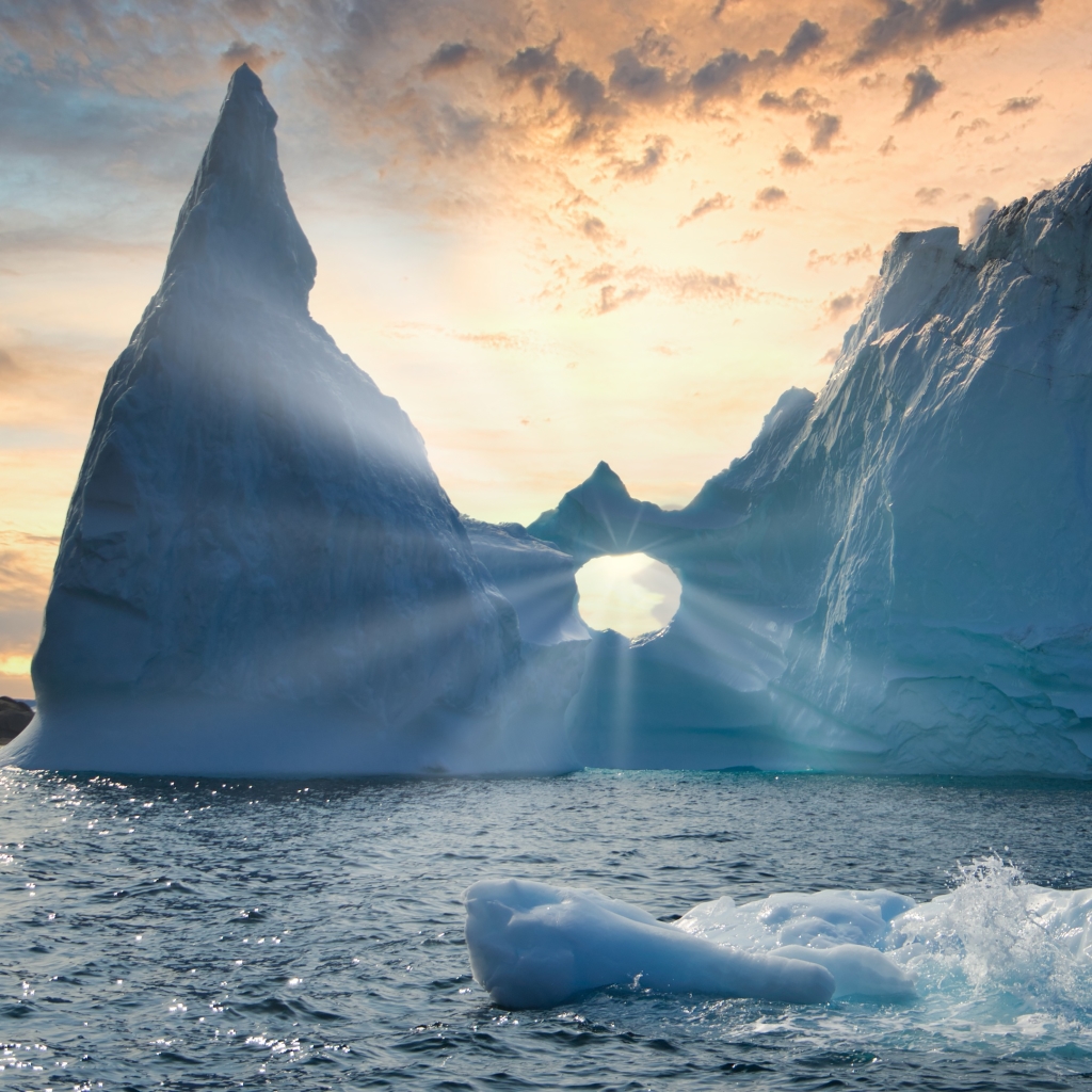 Sun rays shining through a hole in an iceberg