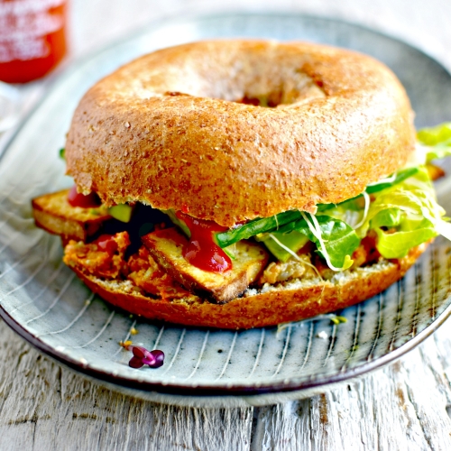 Bang bang tofu bagel with sriracha-lime peanut butter, avocado and thinly shredded vegetables