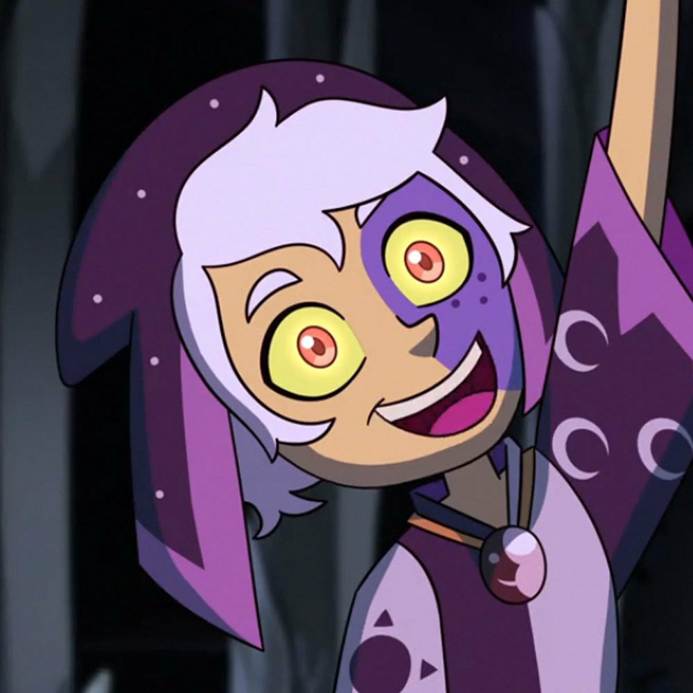 Forum avatar of The Collector from the TV show The Owl House: wide-eyed grin, pale hair and purple hooded robe adorned with moon motifs.