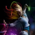 A dynamic and artistic profile photo featuring a woman in motion, with vibrant colors and ethereal effects highlighting her expressive pose.