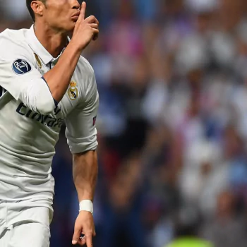 Forum avatar of a soccer star in Real Madrid white kit, cropped mid-torso, shushing the crowd with a finger to his lips against a blurred stadium background.