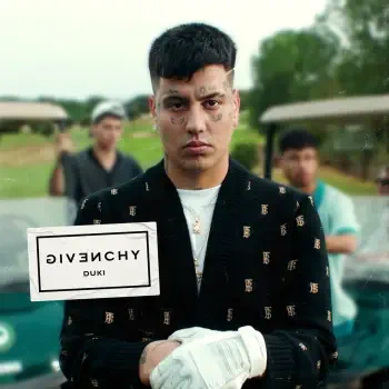 A rapper with tattoos and a confident expression stands in front of a golf cart, wearing a Givenchy sweater. The image is tagged with music and Duki.