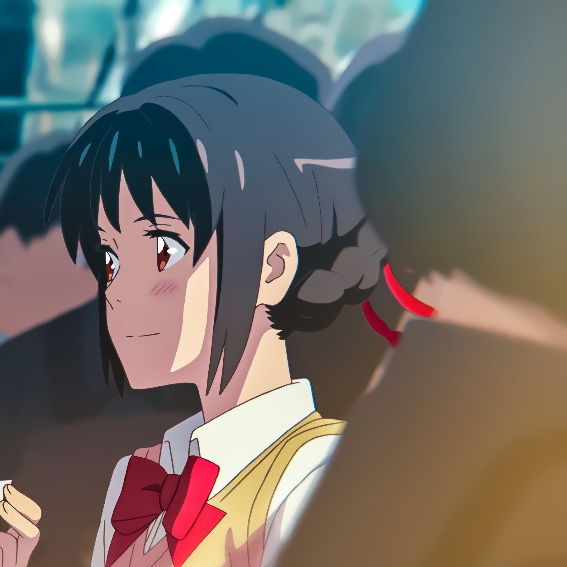 Anime profile photo featuring Mitsuha Miyamizu from Your Name. She smiles softly, surrounded by a blurred crowd, capturing her warmth and charm.