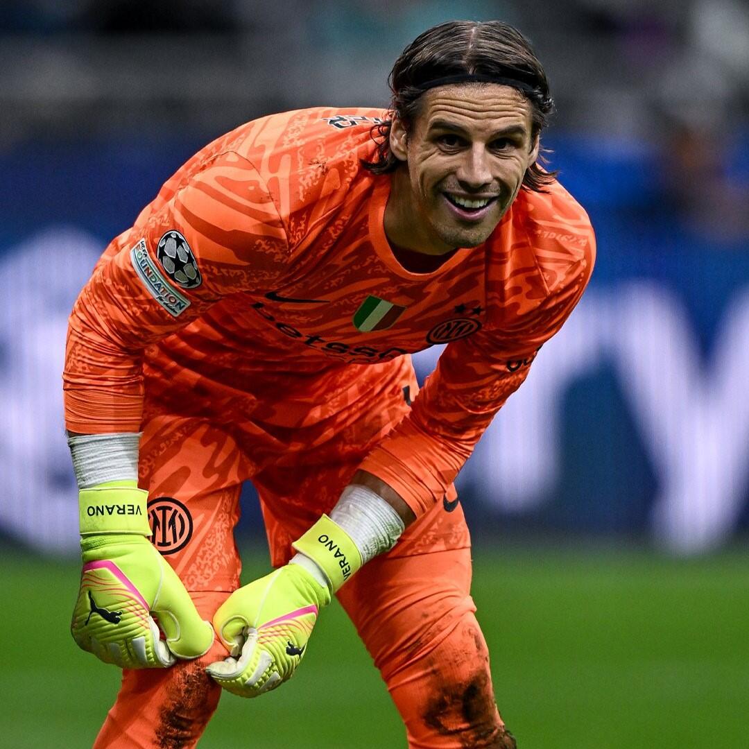 Yann Sommer in an orange Inter Milan goalkeeper jersey and gloves, crouched and focused on the soccer field.