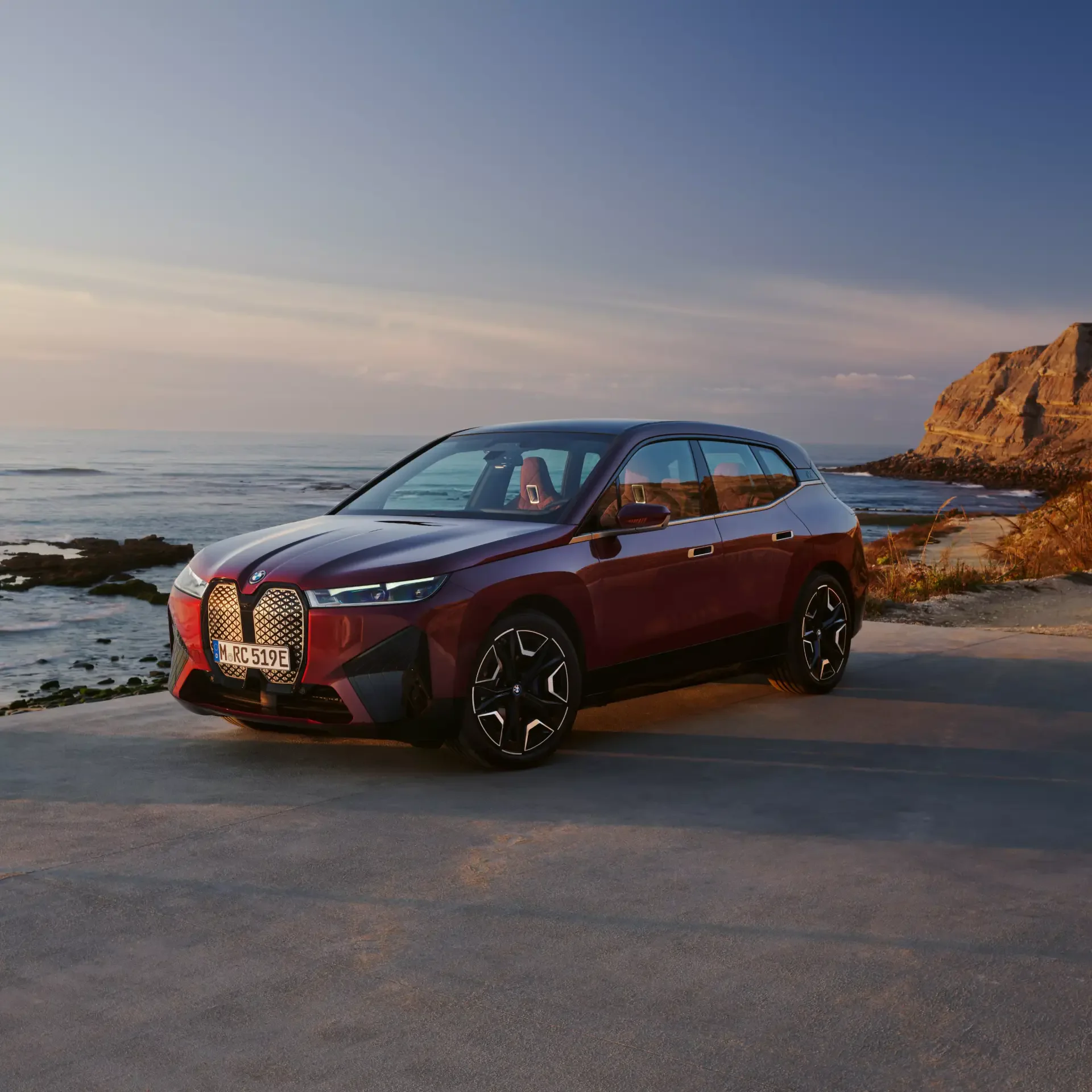 Red BMW car parked by a rocky coastline at sunset, used as a forum avatar.