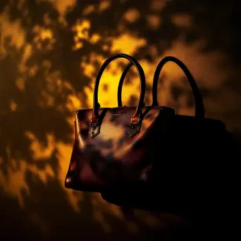 A stylish handbag with slender handles casts a soft shadow against a warm, textured background, making it a striking choice for a forum avatar or profile photo.