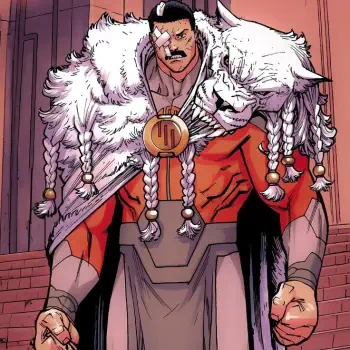 Image Comics character Thragg, depicted as a muscular figure in a red and cream outfit, adorned with a fur cloak and a distinctive medallion, striking a powerful pose.