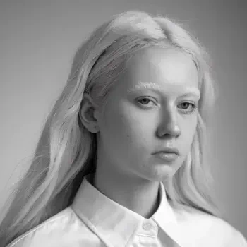 A monochrome profile photo featuring a young person with long, light hair and a white shirt, embodying a minimalist white aesthetic suitable for a forum avatar.