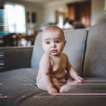 A cute baby sits on a couch, gazing softly at the camera, making this an engaging forum avatar or profile picture.