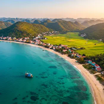 Aerial view of a serene beach in Vietnam, showcasing clear turquoise waters, lush green hills, and a small fishing boat near the shore. Perfect profile photo for a Vietnam-themed avatar.