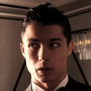 Close-up portrait of soccer player Cristiano Ronaldo with slicked-back hair, wearing a formal suit, set as a forum avatar or profile photo.