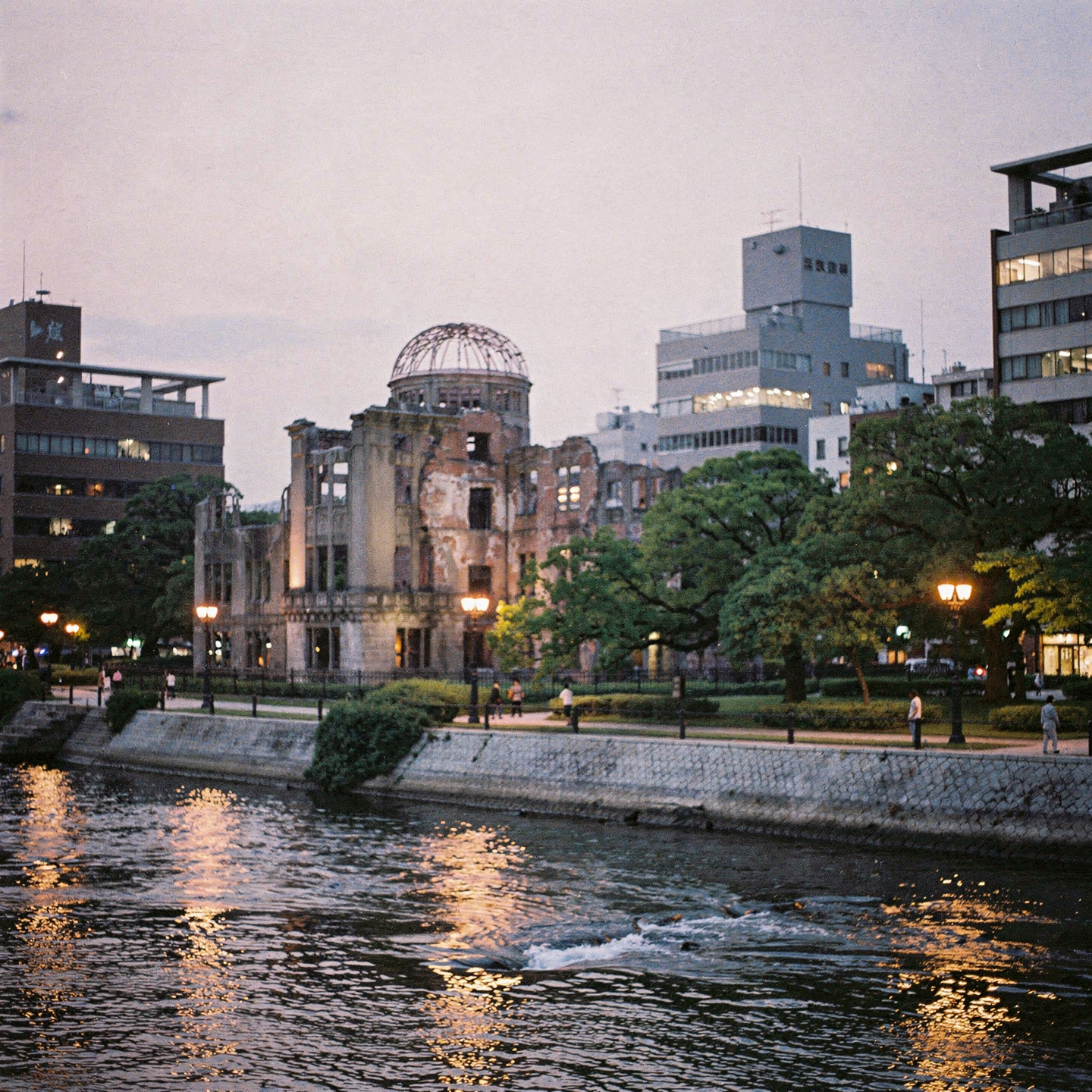 Forum profile photo of Hiroshima's Atomic Bomb Dome at dusk, river reflections, glowing walkways and surrounding modern buildings.