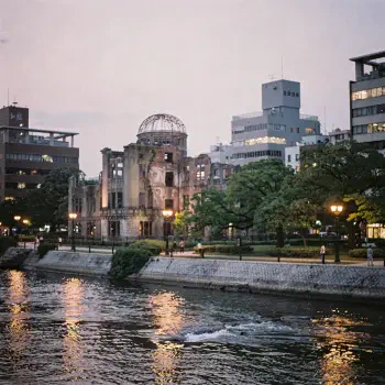 Forum profile photo of Hiroshima's Atomic Bomb Dome at dusk, river reflections, glowing walkways and surrounding modern buildings.