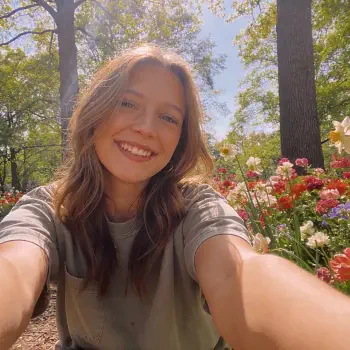 Selfie of a smiling person in a sunlit flower garden, shown as a forum avatar/profile picture.