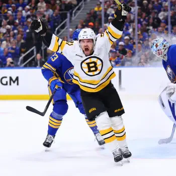 Forum avatar of a sports hockey scene: NHL Boston Bruins player in white jersey raising arms in celebration on the ice, opposing blue team and goalie visible in background.