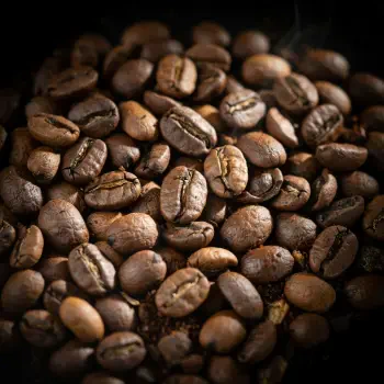 Forum avatar/profile photo: close-up of roasted coffee beans, warm brown and textured, clustered against a dark background.