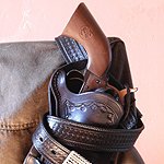 Forum avatar/pfp: The Dark Tower–themed comic image — close-up of a worn leather holster with ornate belt buckles and layered straps against a pale pink background.